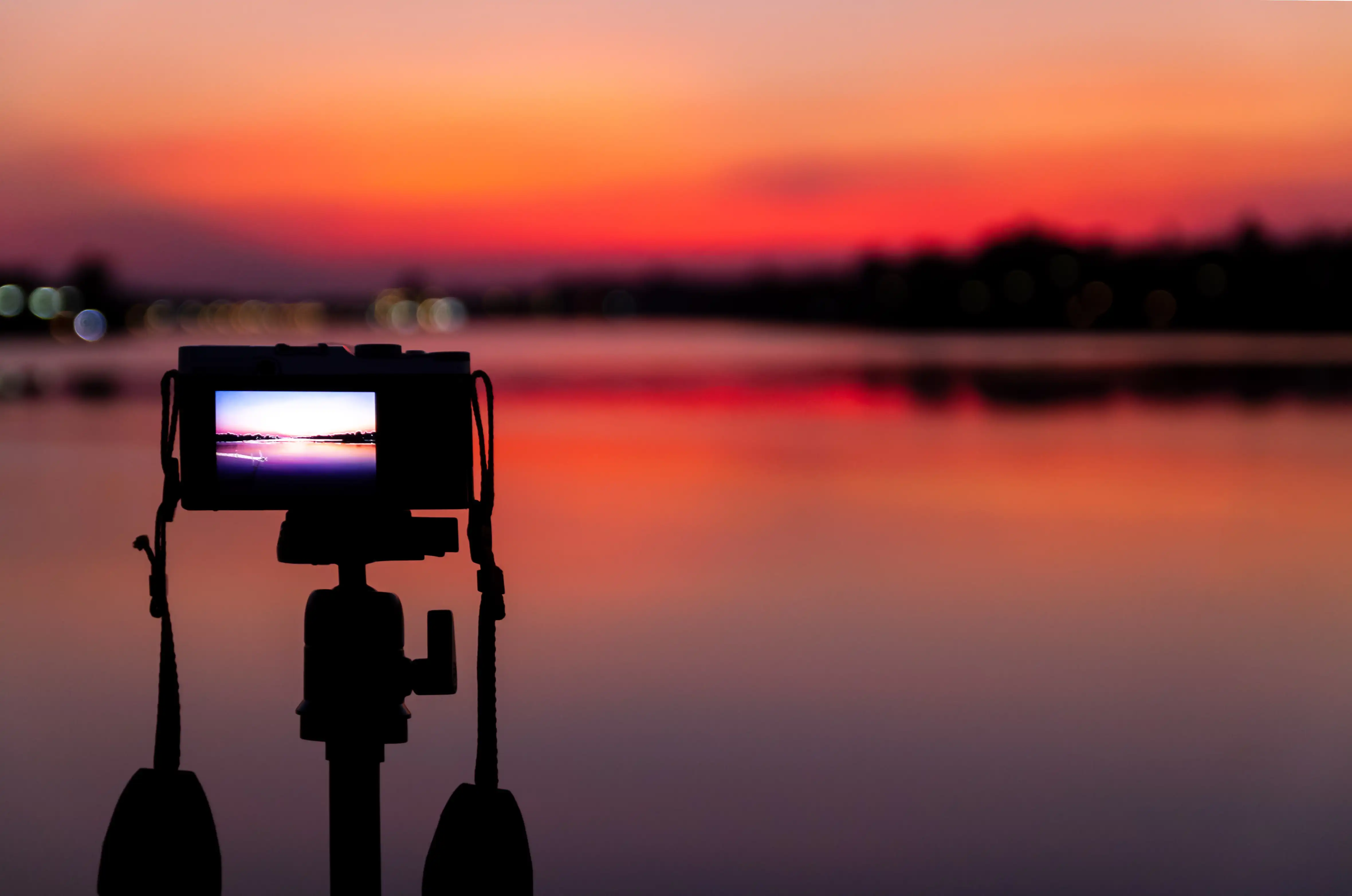 Camera capturing sunset over calm lake
