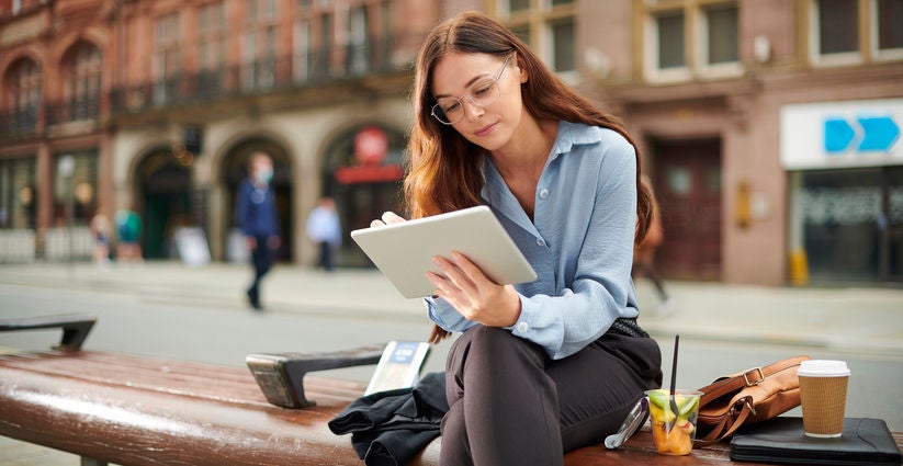 Woman using tablet outdoors on bench