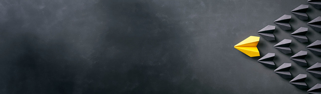 Conceptual photography with black and yellow paper airplanes on a smudged blackboard.